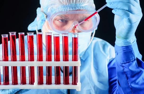 Korumacı bilim adamı kan örneğini analiz ediyor. Laboratuvar teknisyeni test tüplerini rafa kaldırdı..
