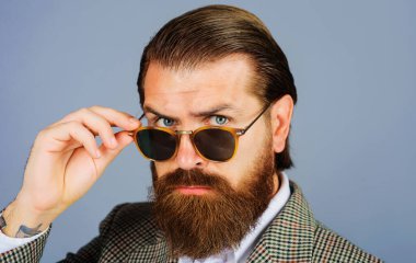 Güneş gözlüklü yakışıklı sakallı adam. Takım elbiseli şık bir iş adamı. Erkek modası.