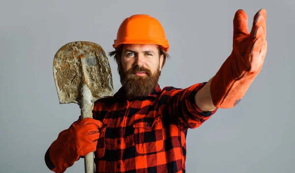 Builder in protective helmet and work gloves with shovel. Bearded workman in hard hat with spade. — Stock Fotó