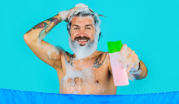 Baard man in de douche met shampoo fles. Een gelukkige man met schuim op zijn hoofd. Haar wassen. Haarverzorging. Kuuroord. — Stockfoto