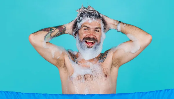 Happy bearded man washing hair with anti-dandruff shampoo. Taking shower. Morning routine procedure.