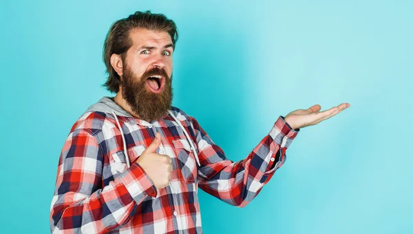 Gelukkig bebaarde man houdt iets op open handpalm en toont duim omhoog. Seizoen verkoop en korting. — Stockfoto