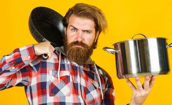 Yemek hazırlamak için mutfak aletleri. Kızartma tavası ve esrarlı sakallı adam. Kızartma tavası ve tencere.