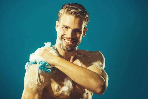 Glimlachende man wassen lichaam met hydraterende gel en washandje onder de douche. Goedemorgen routine. Kuuroord. — Stockfoto