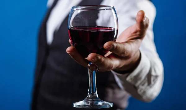 Man hand with glass of red wine. Tasting alcohol. Wine tour. Male sommelier with wineglass. Closeup