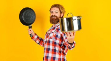 Gülümseyen erkek şef tencere ve tava. Kızartma tavası ve tenceresi olan sakallı adam. Mutfak aletleri