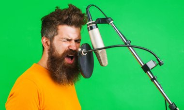 Profesyonel vokalist mikrofonda şarkı söylüyor. Müzik üretimi konsepti. Sakallı adam şarkı söylüyor.