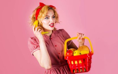 Market. Alışveriş sepeti dolusu yiyecek taşıyan güzel bir kadın muz tutuyor. Süpermarket ya da mağaza