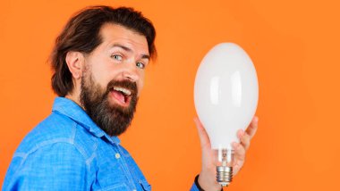 Kot gömlekli, ampullü yakışıklı sakallı adam. Enerji verimliliği ve elektrik. İyi fikir.