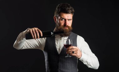 Sakallı adam şarap kadehinde kırmızı şarap dolduruyor. Şarap, şarap imalatçısı. Sommelier alkol tadıyor.
