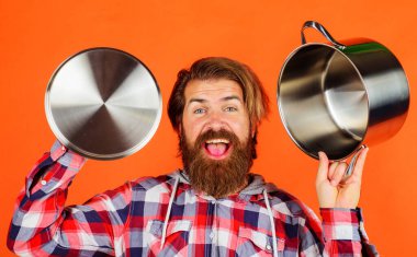 Esrarlı ve kapaklı mutlu sakallı adam. Tencereli bir erkek aşçı. Yemek pişirmek. Mutfak eşyaları.