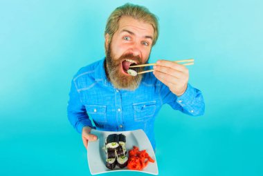 Sakallı adam bir tabak suşi ve zencefil turşusu ile. Çubukla makarna yiyen adam.