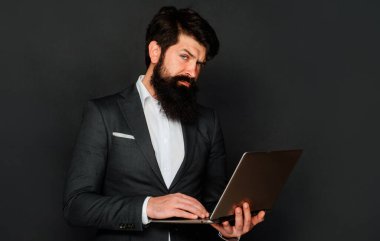 Dizüstü bilgisayarı olan ciddi bir adam. İşadamı ofiste defterle çalışıyor. Teknoloji ve İnternet