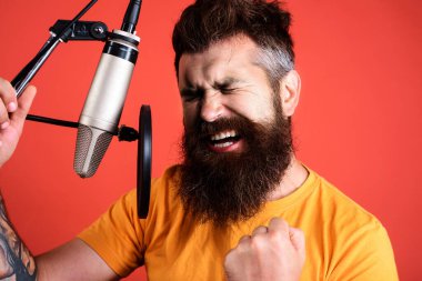 Emotional male singer singing in condenser microphone. Professional vocalist in studio. Music
