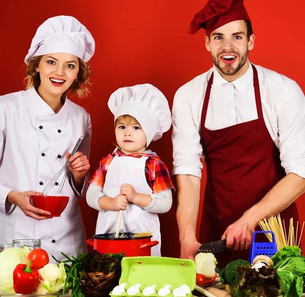 Happy family preparing healthy food in kitchen at home. Mother and father teach little son cooking