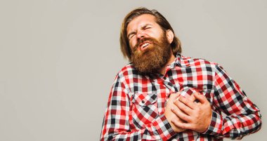 Bearded man with heartache holding hand on chest. Heart attack or stroke. Health care concept