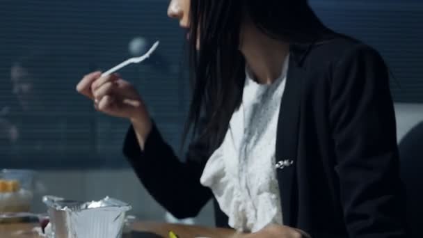 Mujer de negocios comiendo en el lugar de trabajo.Mujer joven en una hermosa oficina moderna cerca de la ventana panorámica cena y examina documentos — Vídeo de stock