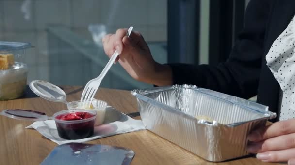 Geschäftsfrau sitzt mittags im Büro am Panoramafenster und taucht Käsekuchen in saure Sahne — Stockvideo