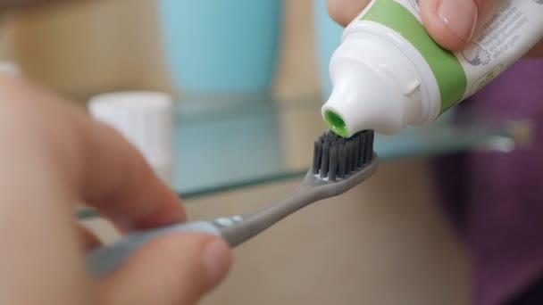 Kobiece ręce w łazience wyciskają zieloną pastę do zębów z tubki na szczoteczkę do zębów czyści zęby, rano i wieczorem zabiegi, higiena. — Wideo stockowe
