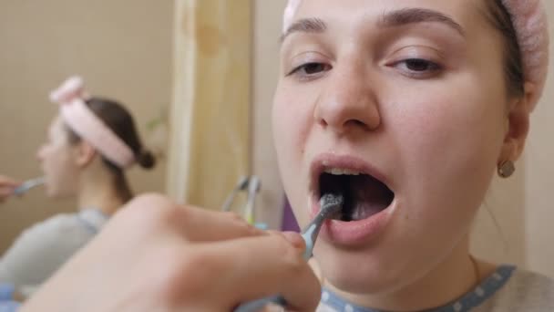 Mujer joven cepillándose los dientes en el baño.Cuidado dental diario — Vídeo de stock