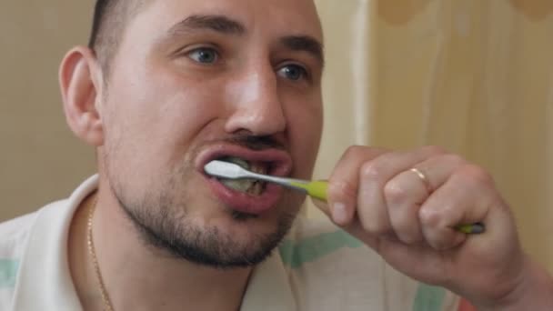Hombre cepillarse los dientes en casa en el baño por la mañana — Vídeos de Stock