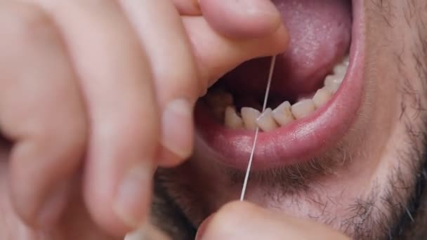 Ежедневное здравоохранение. Человек чистит зубы зубной нитью — стоковое видео