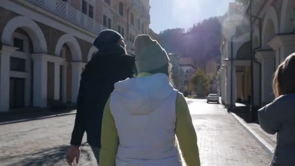 Widok z tyłu.Troje turystów spaceruje piękną ulicą w Europie, odwiedzając małe miasteczko. Przyjaźń, spacery, turystyka, radość. Zwolniony ruch — Wideo stockowe