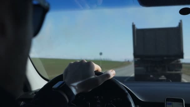 Kierowca, człowiek w okularach, prowadzi ciężarówkę wzdłuż drogi, kontroluje pas ruchu i jest chroniony przed słońcem — Wideo stockowe
