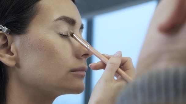 De ogen van een jong vrouwelijk model tijdens de make-up. Een professionele make-up kunstenaar brengt schaduwen aan op het bovenste ooglid van de modellen ogen met een zachte borstel — Stockvideo