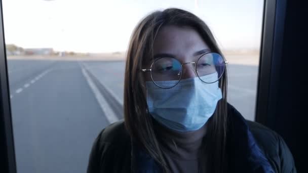 Une jeune femme portant un masque de protection prend le bus de l'aéroport. Voyage, mouvement, pendant l'infection par le coronavirus. — Video