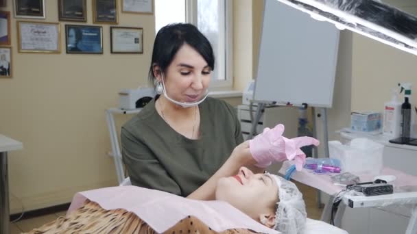 Le médecin cosmétologue consulte un patient dans un salon de beauté avant d'appliquer du pigment sur les lèvres — Video