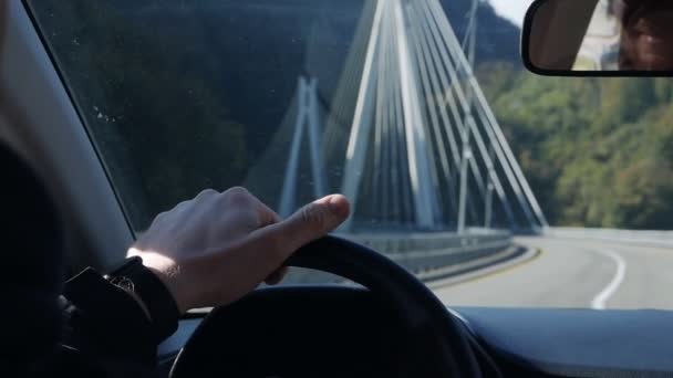 El coche está en el puente. Manos en el volante y el salpicadero de un coche durante el día conduciendo a través del puente. — Vídeos de Stock