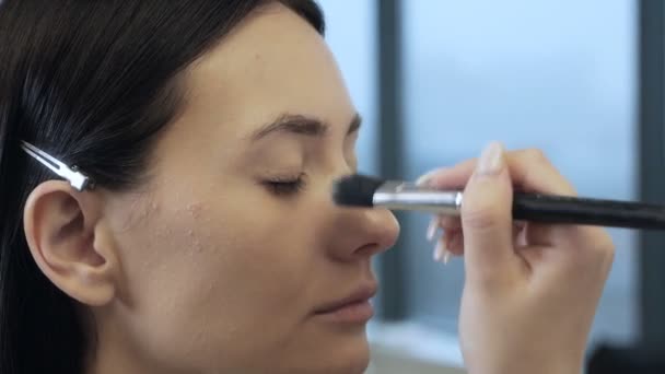 Makeup καλλιτέχνης ή στυλίστας εφαρμόζει θεμέλιο, σκόνη, πινέλο στο πρόσωπο μοντέλα. Επαγγελματικό μέικ-απ. Εργαστήριο κατάρτισης μακιγιάζ — Αρχείο Βίντεο