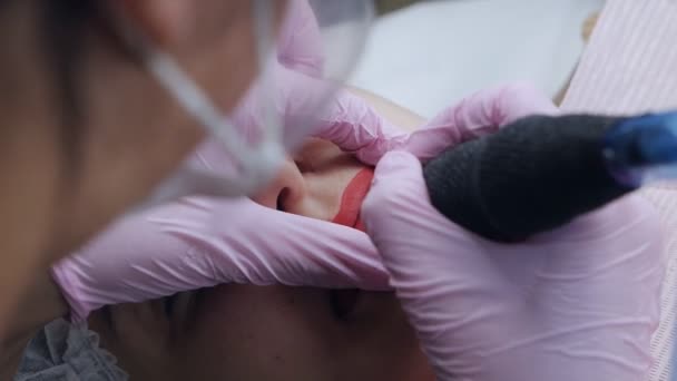 Рука делает постоянный макияж губы процедура нанесения пигмента макияж на губы с татуировкой машины — стоковое видео
