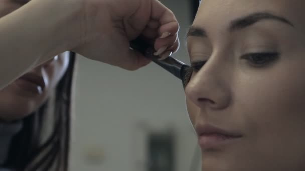 S speciální make-up štětcem, profesionální make-up umělec dělá make-up pro krásnou ženskou modelku, stínování, zvýrazňovač, nadace na nose, lícní kosti — Stock video