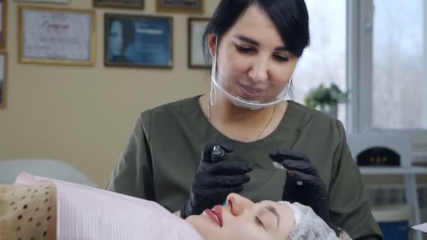 Косметолог наносит постоянный макияж на брови в салоне красоты. Постоянная косметическая процедура в современном салоне красоты — стоковое видео