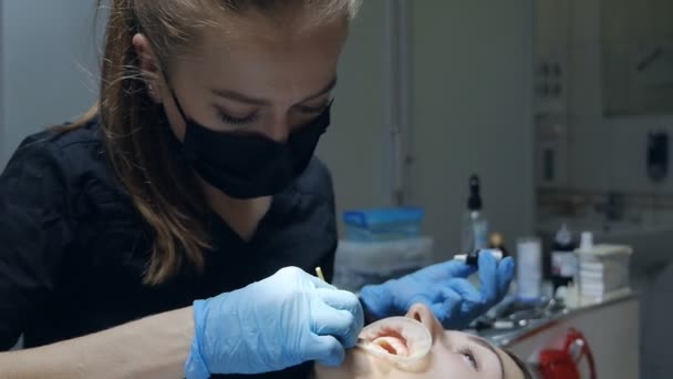 Mujer joven dentista aplica gel en los dientes de los pacientes en la odontología moderna — Vídeo de stock