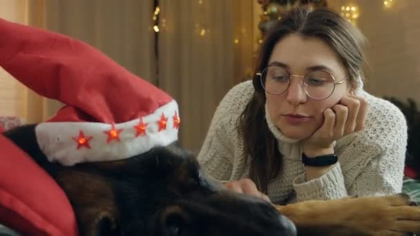 若い女性は病気の犬と家でクリスマスと新年を祝う 悲しい夢のようなお祝いの夜 — ストック動画