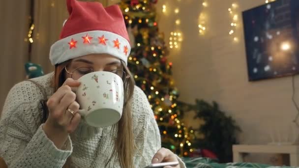 Woman Red Santa Claus Hat Lies Sofa Looks Screen Phone — Stock Video