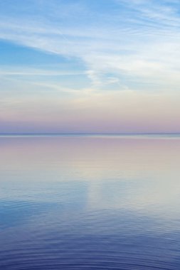 Denizde güzel bir gün batımı, suda pastel renkler ve yansımalar, renkli bulutlar ve deniz ile sakin doğa manzarası. Çevrenin doğal eğilimi. Soyut arkaplan.
