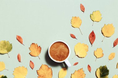 Sonbahar kompozisyonu, bir fincan kahve ve sonbahar yapraklarıyla. Sıcak atmosfer ve sütlü sıcak kahve. Minimum düzlük, sonbahar konsepti. Boşluğu kopyala
