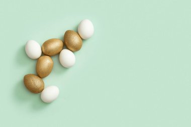 Yeşil arka planda altın ve beyaz Paskalya yumurtaları. Mutlu Paskalyalar, kartpostal, fotokopi alanı şablonu. Üst manzara, düz uzanma.