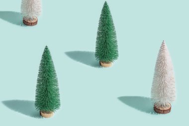 Açık mavi naneli arka planda yeşil ve beyaz renkte Noel ağaçlarının olduğu en küçük desen. Yeni yıl konsepti.
