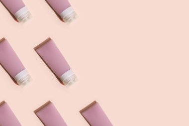 Krem, jöle ve losyon için kozmetik şişeli desen. Güzellik ürünleri paketi, pembe arka planda sert gölgeli plastik kap, tek renkli resim.