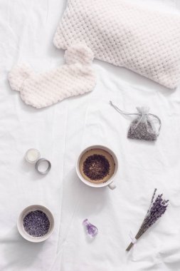 Yatmadan önce dinlenmek için fincanda sağlıklı bitkisel lavanta çayıyla yatıyordu. Uyku maskesi ve balsam beyaz çarşaflarda gerekli yağ ile.