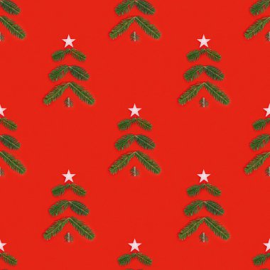 Çam dallarından gelen yeşil Noel ağacı ve kırmızı arka planda yeni yıl köknar ağacı olan yaratıcı, kusursuz bir Noel deseni. Minimum kış tatili