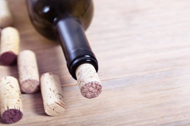 Şişe şarap ve mantarlar eski ahşap masaüstünde fotokopi alanı ile kapanır. Yumuşak odak.