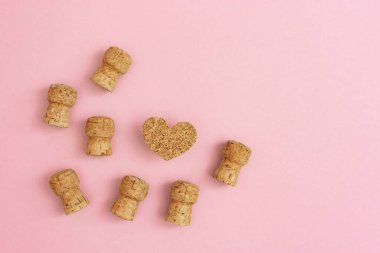 Şampanyadan mantarlar köpüklü şarap ve mantar malzemeden ahşap kalp pembe arka planda metin için fotokopi alanı. Tatil tebrik kartı. Yukarıdan görüntüle.