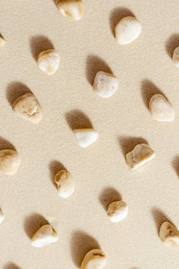 Pattern with pebble sea stones on fine sand. Natural stone neutral beige yellow color, monochrome tones. Summer minimal design background, concept for meditation and relaxation, spa. View from above clipart