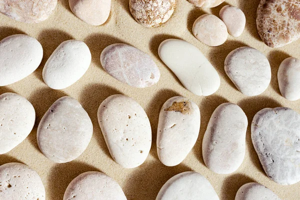 Pattern with pebble sea stones on fine sand. Natural stone neutral beige yellow color, monochrome tones. Summer minimal design background, concept for meditation and relaxation, spa. View from above